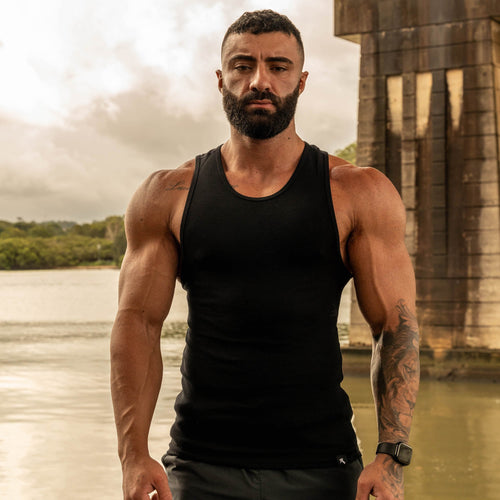front pose showing muscular physique in LionBuilt black tank top by water