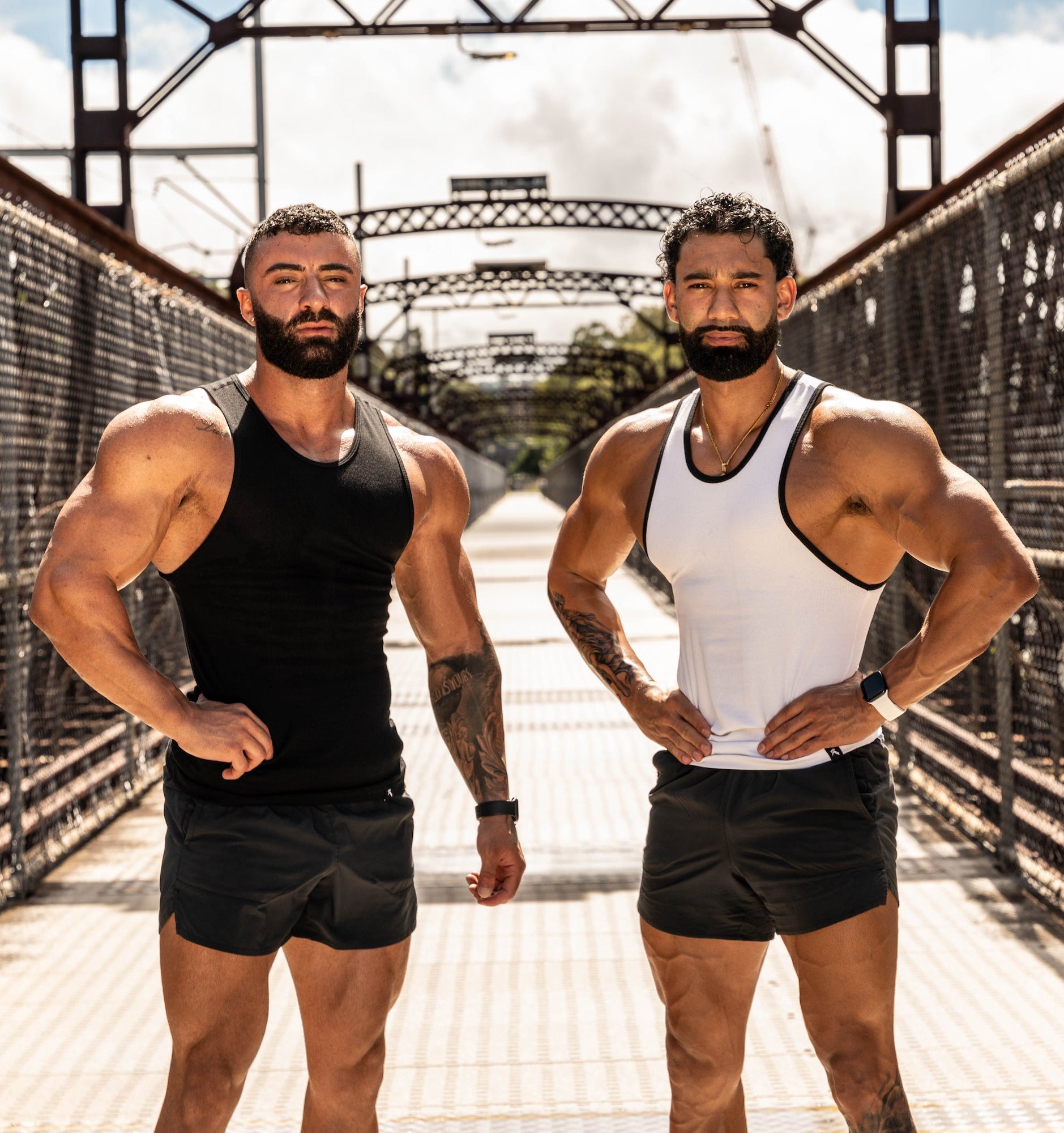 Two muscular men posing on a bridge