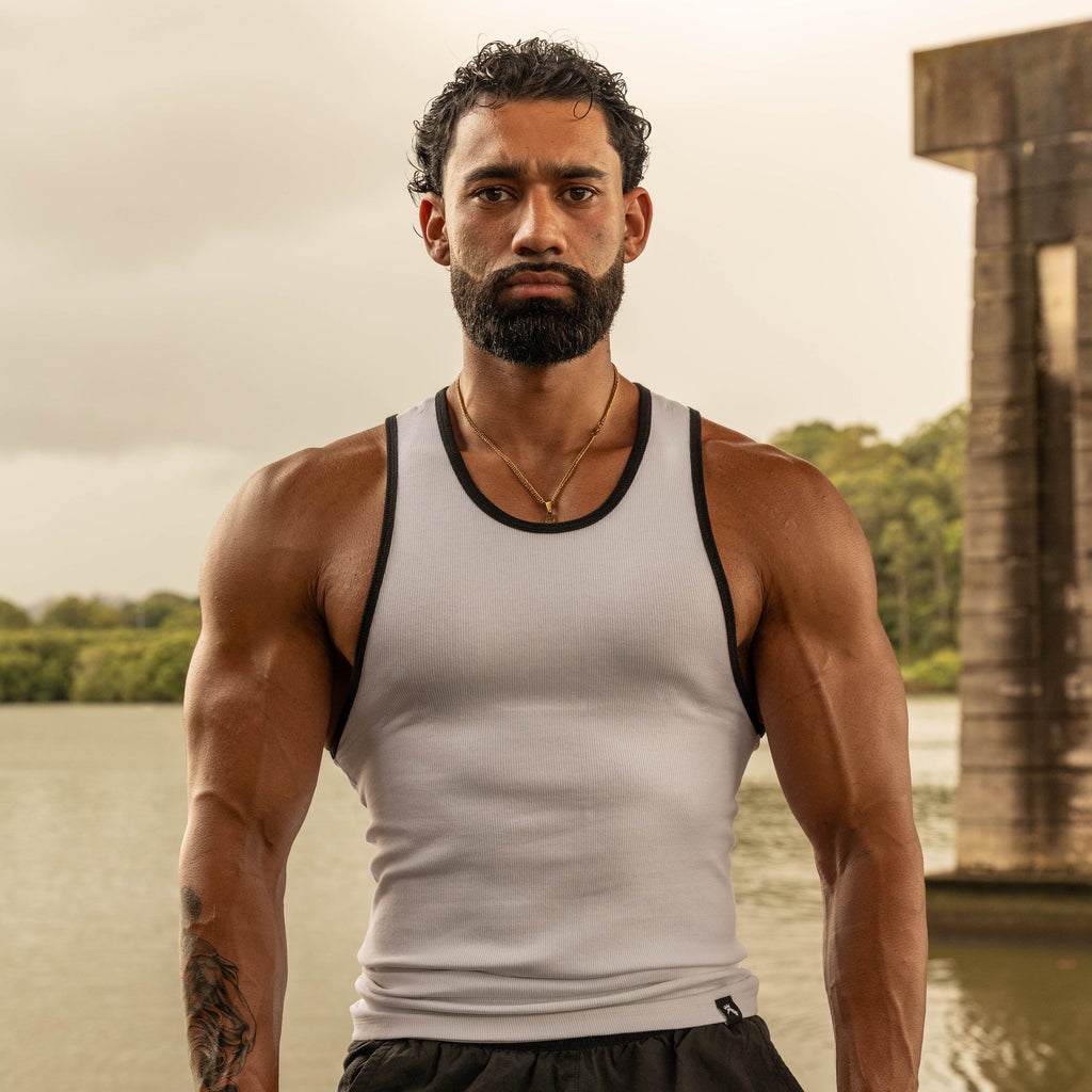 front pose showing muscular physique in LionBuilt white tank top by water